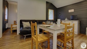 Un espacio habitable compacto con comedor, kitchenette y una pared de madera oscura.