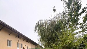 Ein Gebäude mit sandfarbener Fassade, einem Kiesweg und einer Rasenfläche mit zwei Liegestühlen.