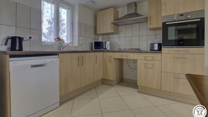 Eine moderne Küche mit hellen Holzschränken, einer eingebauten Mikrowelle, einem Geschirrspüler und einem Edelstahlbackofen.