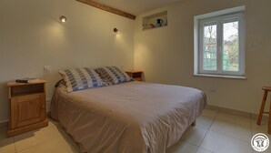 Ein Schlafzimmer mit einem Bett, Holznachttischen, einem Regal mit Büchern und einem Fenster.