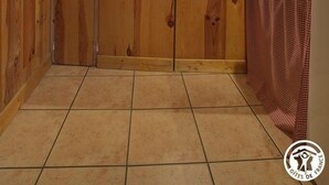 A compact kitchen with wooden cabinets, a microwave, a small window, and a tiled floor.