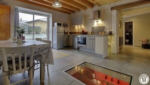 A modern kitchen with wooden beams, a dining area, and a view of the outside. - des Grands Cours - Marboz (MARBOZ)