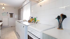 Ett kök med tvättmaskin, spis och diverse köksredskap på bänkskivan.