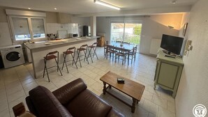 Ett modernt kök med matplats, en bar och ett vardagsrum med soffa och soffbord.