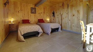 Quarto de madeira com duas camas, uma mesa e uma cadeira.