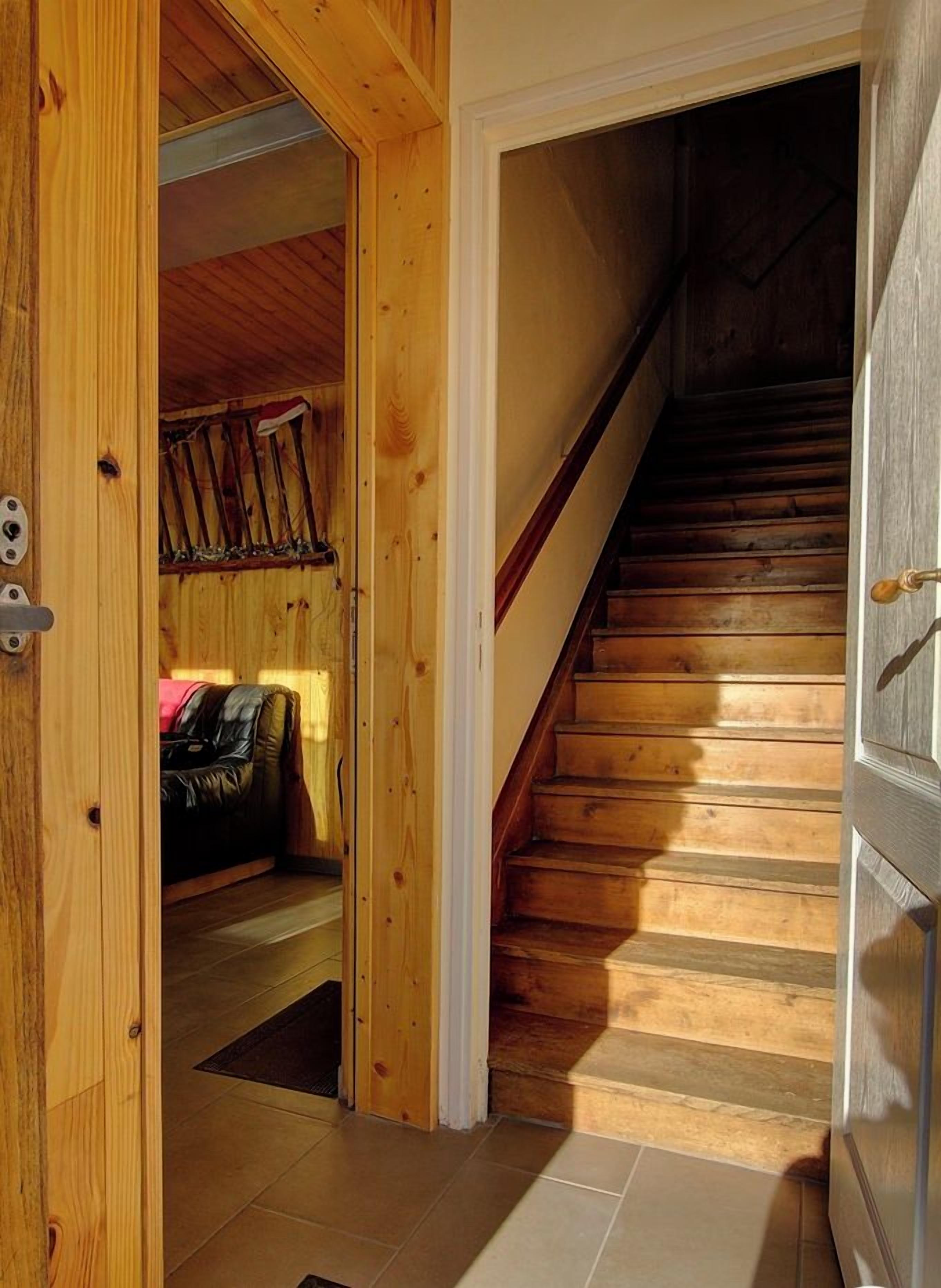 Una escala de fusta que porta a una habitació amb un llit i una perxa.