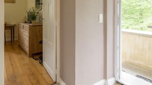 A room with a wooden floor, a door leading to a bathroom, a small table with a mirror, and a window with a view of greenery. - la Grande Fontaine - Ceyzeriat (CEYZERIAT)