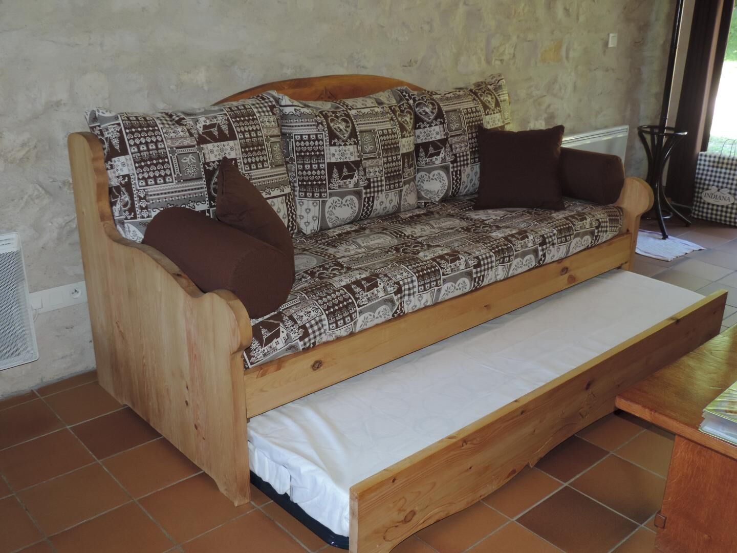 Un canapé en bois avec des coussins à motifs et un matelas blanc.