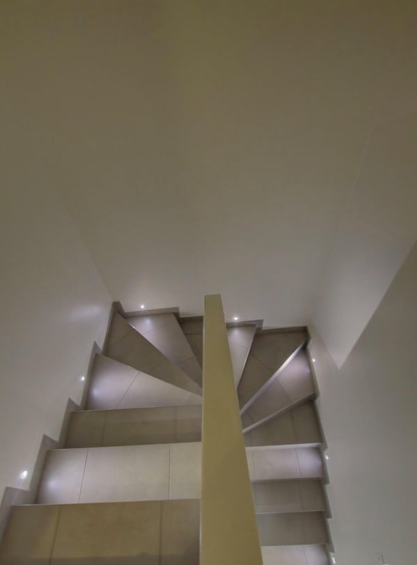 A modern staircase with a geometric design, leading to an upper floor.