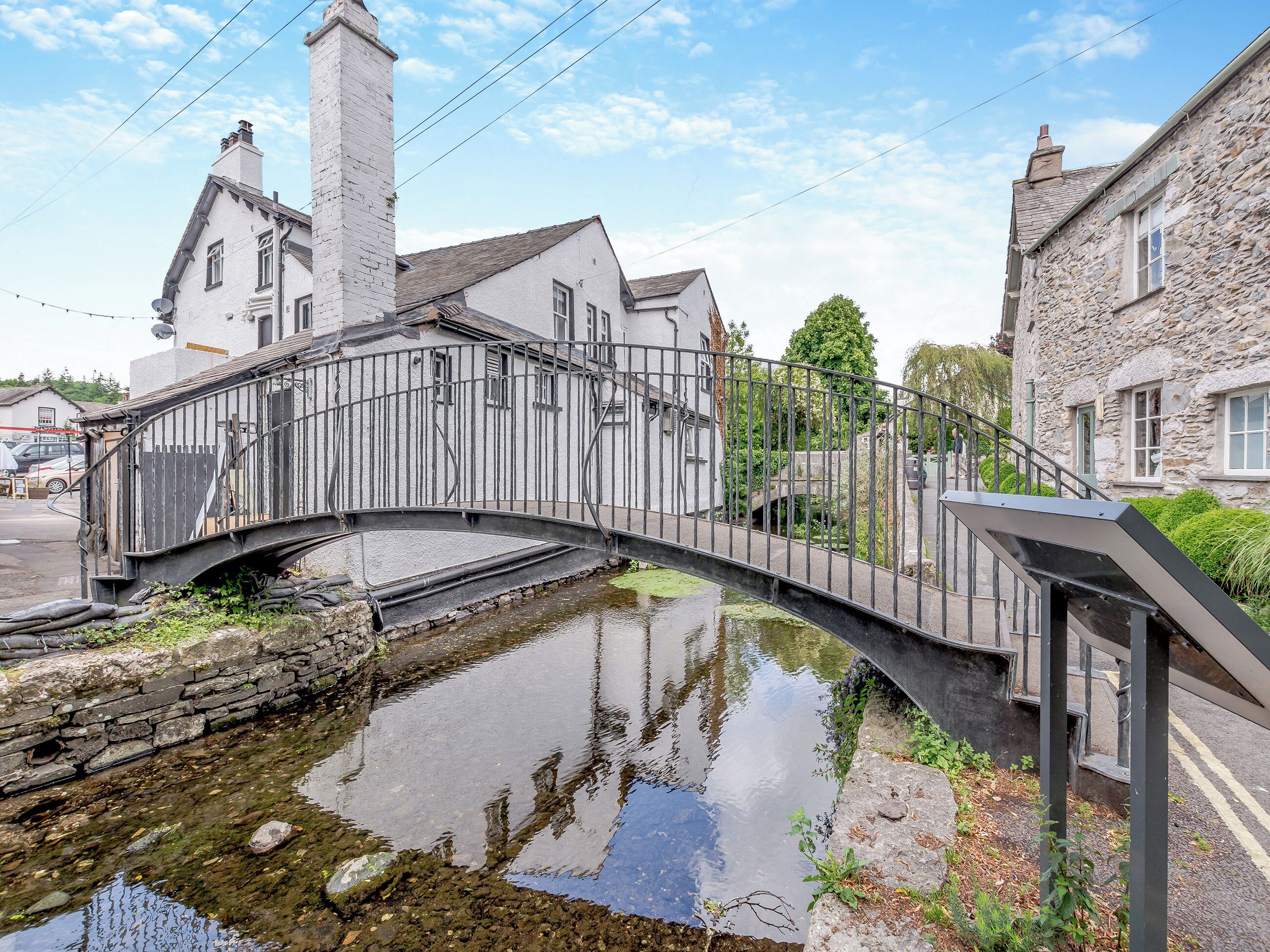 A stone bridge over a calm waterway, surrounded by traditional stone buildings with chimneys.