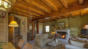 A cozy living room with a fireplace, comfortable seating, and a dining area. - Les Epées - Conzieu - Gîte (CONZIEU)