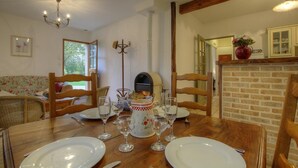 A dining area with a wooden table set for four, a fireplace, and a view of the outdoors.