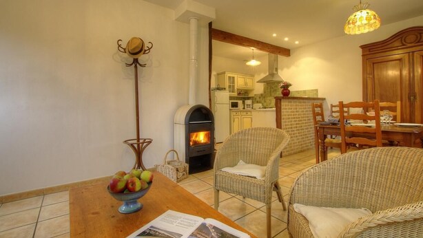 A cozy living room with a fireplace, wicker furniture, and a dining area with a wooden table and chairs.