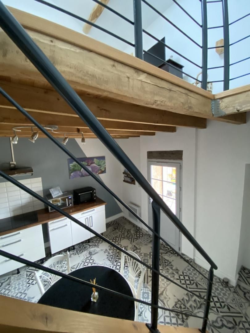 Ein mehrgeschossiges Interieur mit Treppe, Küchenbereich und gemustertem Boden.