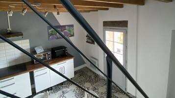 Ein mehrgeschossiges Interieur mit Treppe, Küchenbereich und gemustertem Boden.