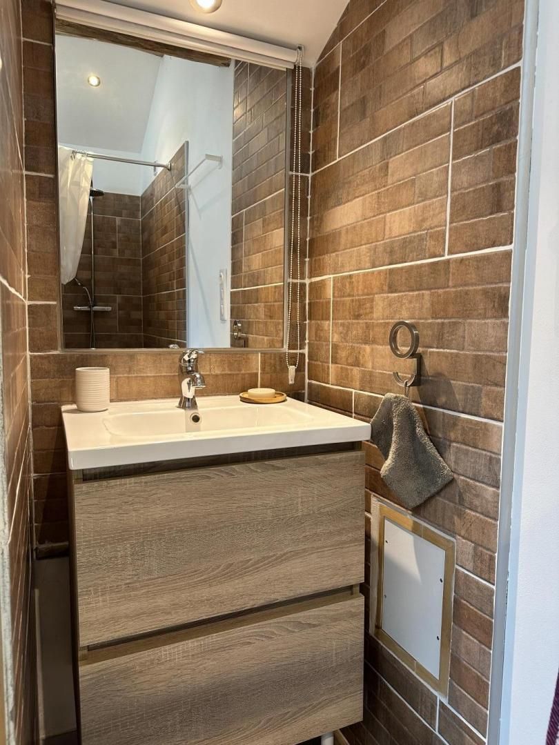 A modern bathroom with a large mirror, a sink, and a towel rack.