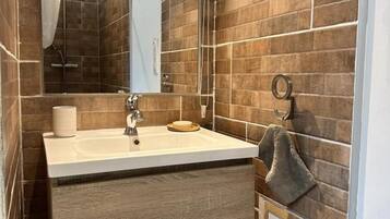 A modern bathroom with a large mirror, a sink, and a towel rack.