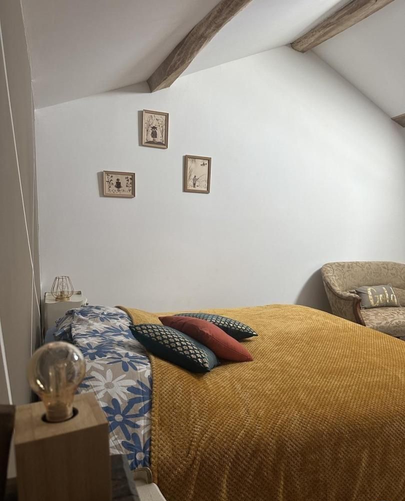 A bedroom with a bed, a chair, and three framed pictures on the wall.