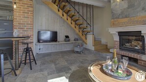 A modern living room with a wooden staircase, a fireplace, a television, and a bar area. - Lacooldouss - Druillat (DRUILLAT)