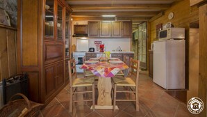 Une cuisine chaleureuse avec des meubles de rangement en bois, une table à manger pour quatre personnes et un réfrigérateur.
