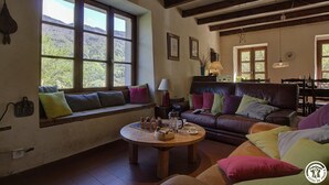 A cozy living room with a large window, a wooden coffee table, and a leather sofa with colorful cushions. - Le Tilleret - Chezery-forens (CHEZERY-FORENS)