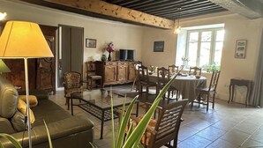 A living room with a sofa, a dining table with chairs, a TV, and a fireplace. - La Maison Forte - Chanoz-chatenay (CHANOZ-CHATENAY)