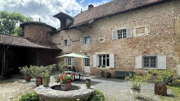 A courtyard with a brick building, a stone well, and potted plants. - La Maison Forte - Chanoz-chatenay (CHANOZ-CHATENAY)