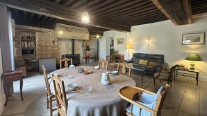 A rustic dining area with a round table, wooden chairs, and a stone wall. - La Maison Forte - Chanoz-chatenay (CHANOZ-CHATENAY)