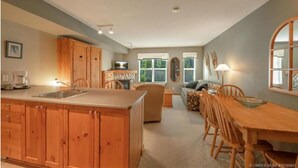 Une cuisine spacieuse avec des meubles en bois, un coin repas avec une table et des chaises, et un salon confortable avec un canapé et une cheminée.