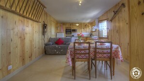 Un interior de madera con comedor, cocina y un altillo.
