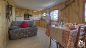Un interior acogedor de madera con sofá, mesa de comedor y zona de cocina.