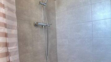 A shower with a handheld showerhead and a wall-mounted faucet.