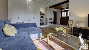 A living room with a blue sofa, a glass coffee table, and a bookshelf.