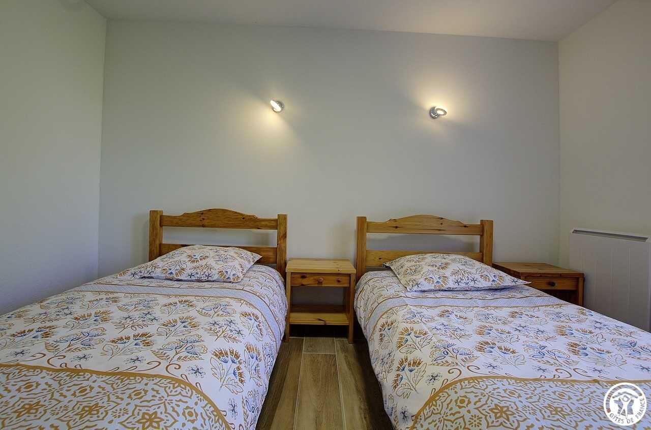 A room with two single beds, each with a wooden headboard and matching nightstands.