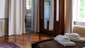 A room with a wooden wardrobe, a bed with a brown headboard, and a window with curtains.