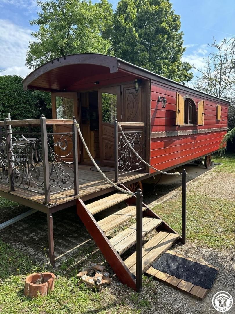 A red wooden boat with a wooden deck and metal railing, featuring a door and windows.