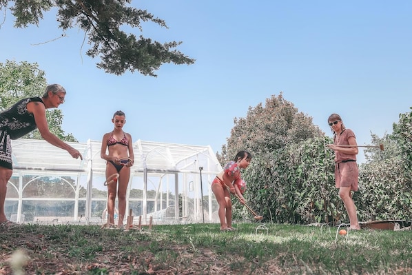 A group of people in a garden with a greenhouse in the background.