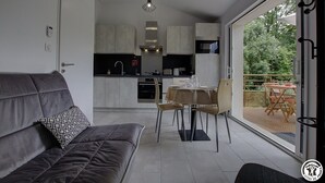 A modern interior with a sofa, dining table, and kitchen area. - Gîte du Buizin - Vaux-en-bugey (VAUX-EN-BUGEY)