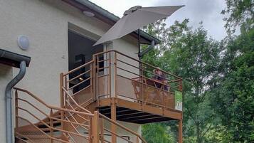 A multi-level outdoor staircase with a metal railing, a potted plant, and a picnic table in the background.