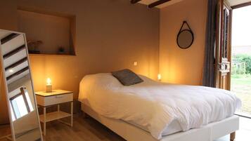 Een slaapkamer met een bed, nachtkastje, spiegel en een hanglamp.