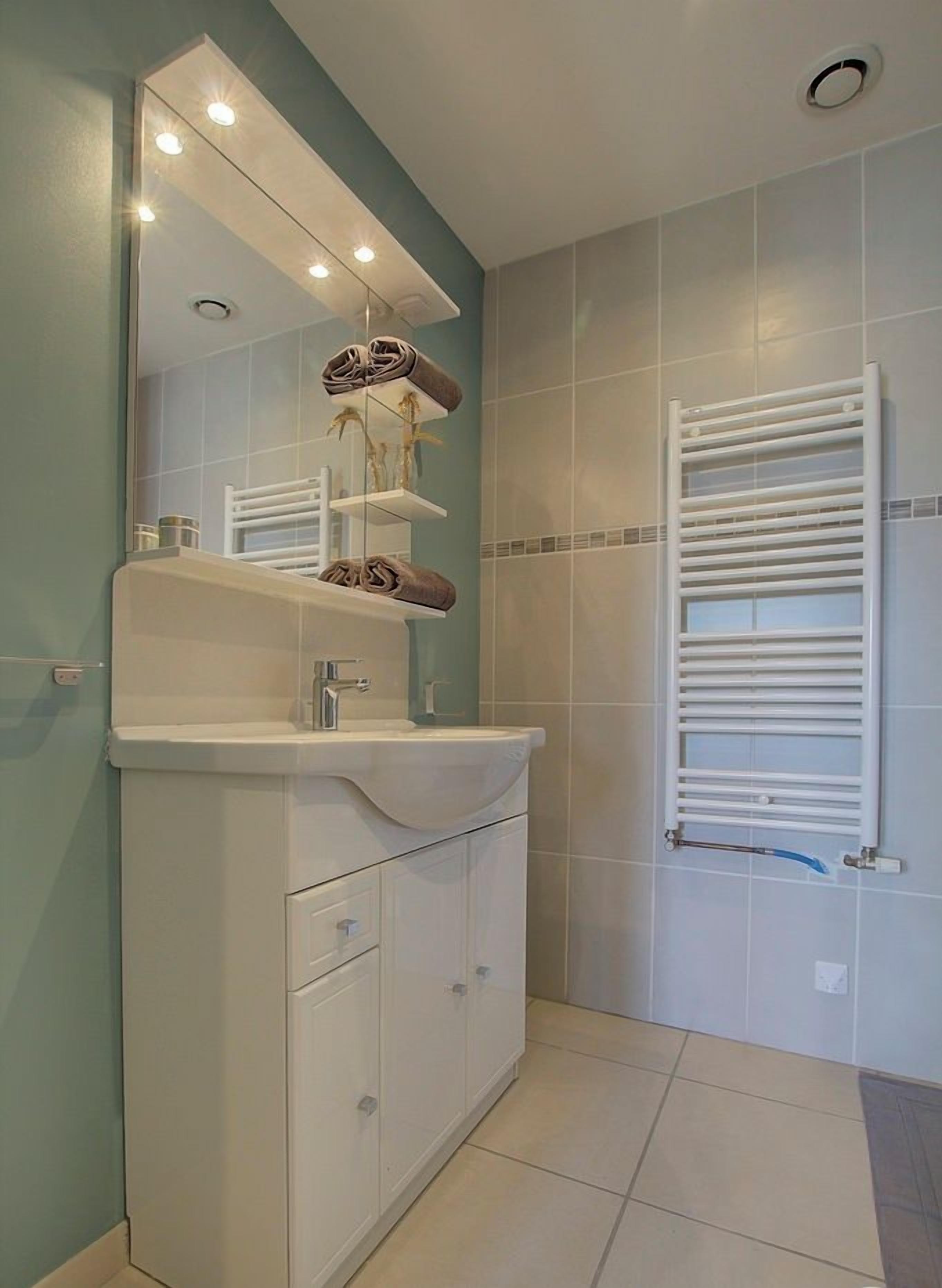 A bathroom with a white vanity, a mirror, and a towel rack.