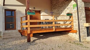 Un balcón de madera con un muro de piedra de fondo, una puerta y un cartel que indica una ubicación GITE.