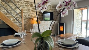 Una mesa de comedor dispuesta con platos, cubiertos y copas de vino, con orquídeas en un jarrón.