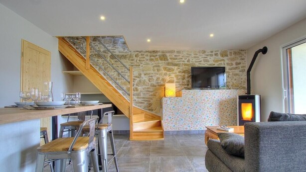 Una cocina con escalera de madera, pared de piedra, televisor y chimenea.