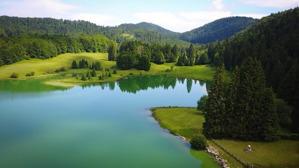 A serene lake surrounded by lush green hills and dense forests.