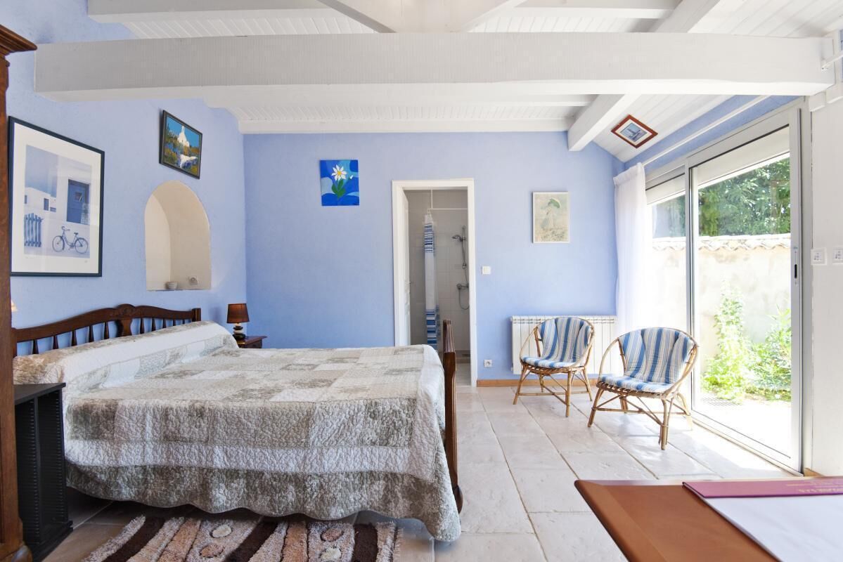 Une chambre à coucher comprenant un lit, une chaise, un radiateur et une porte donnant sur un balcon.
