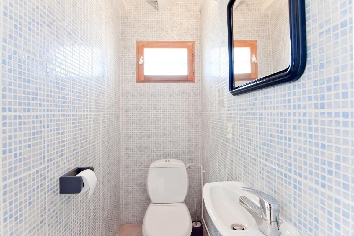 A small bathroom with a toilet, sink, and a window.