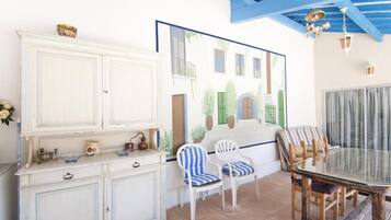 A dining area with a white cabinet, striped chairs, and a glass table.