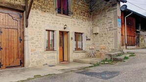 Un edificio de piedra con puerta de madera, ventanas y un pequeño porche.