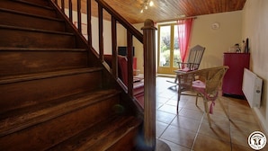 Una escalera de madera que lleva a una habitación con una silla roja y una silla de mimbre.